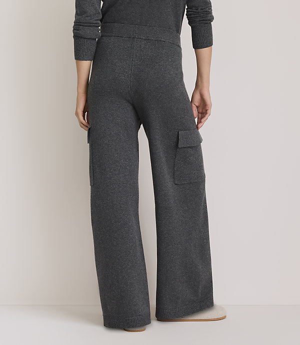 A person wearing dark gray knit cargo pants stands on a light-colored floor, with a plain, light background.