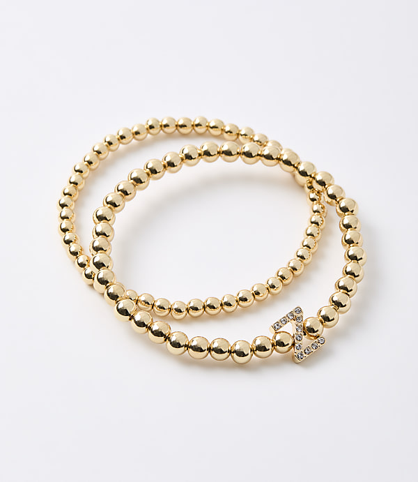 A gold beaded bracelet with a diamond-encrusted clasp is coiled on a plain white background.