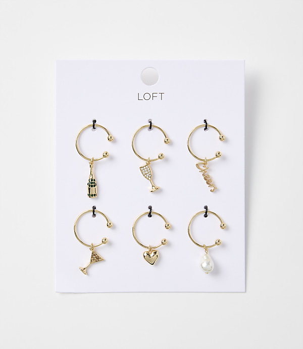 Six gold wine charms, each with a different miniature charm, hang from a white card with the "LOFT" logo at the top.
