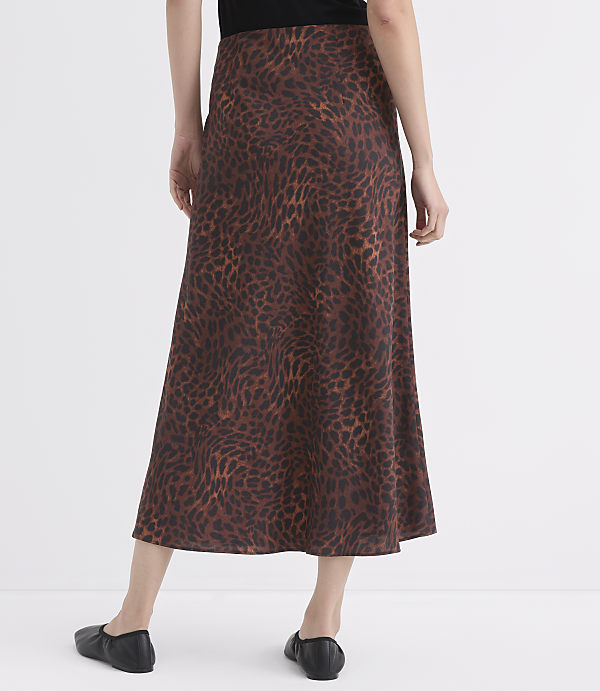 A person wearing a brown leopard-print skirt and black flats stands against a plain white background.
