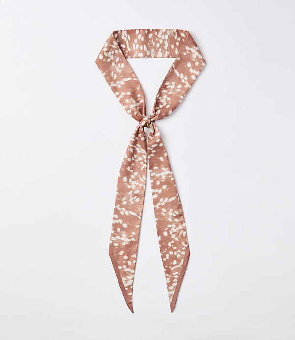 A rust-colored silky scarf with a white speckled pattern is knotted in the center, with its ends hanging down against a plain white background.