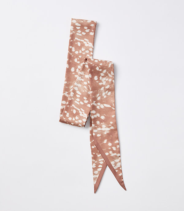 A rust-colored satin scarf with a white speckled pattern lies on a plain white background.