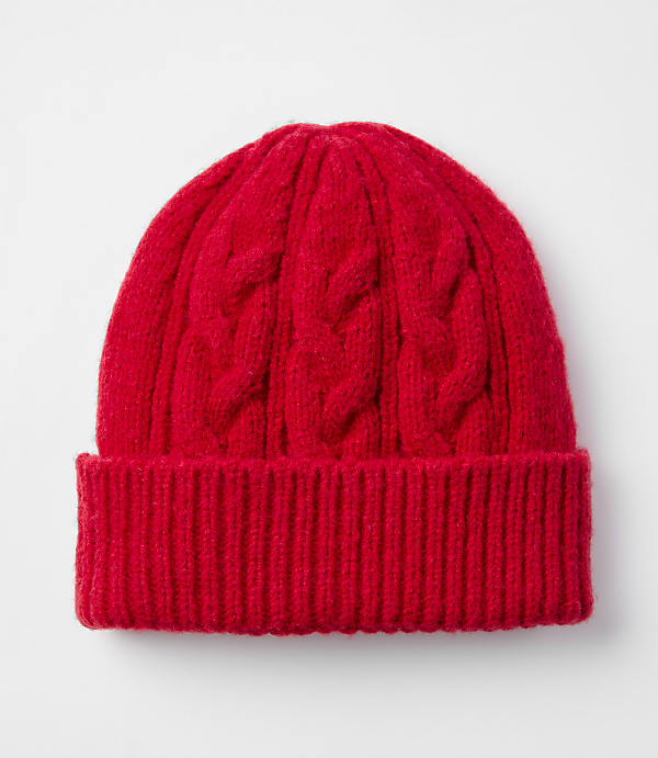 A bright red cable-knit beanie with a ribbed brim rests against a plain white background.