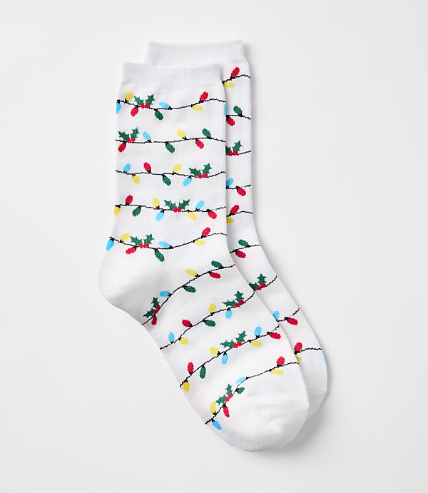 A pair of white socks with a pattern of colorful Christmas lights and holly adorns the foreground, set against a plain white background.