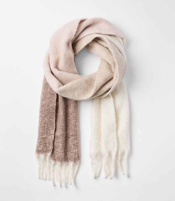 A soft, fuzzy scarf with a gradient of pink, beige, and white hues hangs against a plain white background.