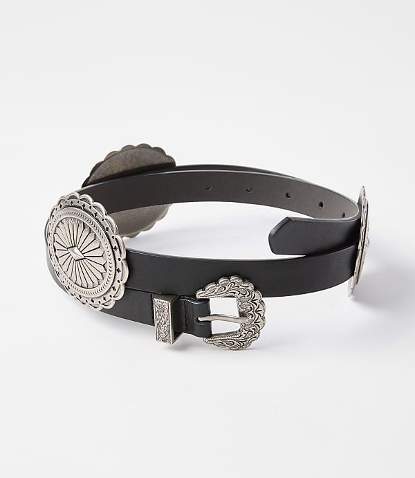 A black leather belt with ornate silver concho embellishments and a buckle rests against a plain white background.