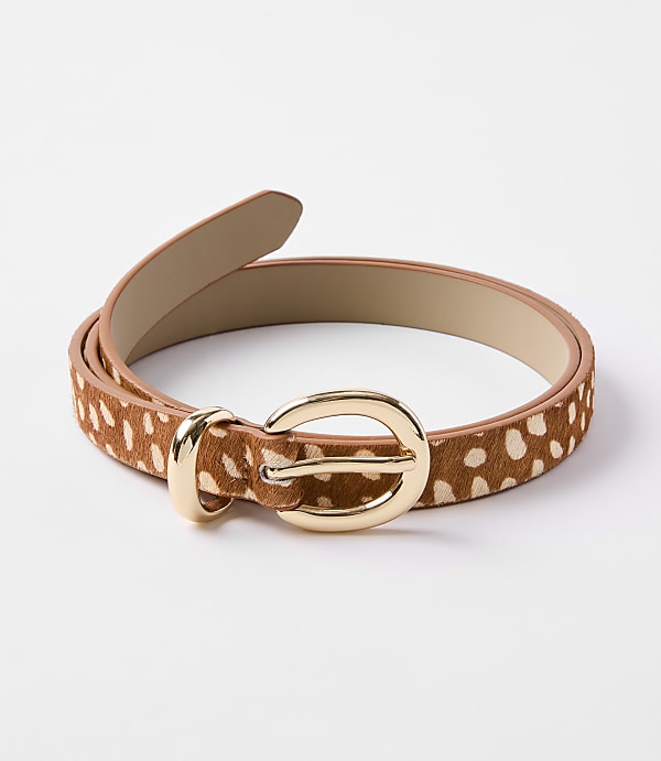A brown and white spotted belt with a gold buckle lies on a plain white background.