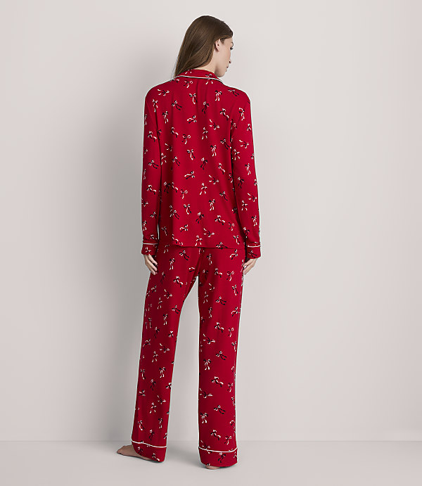 A woman in red patterned pajamas stands against a plain white background.