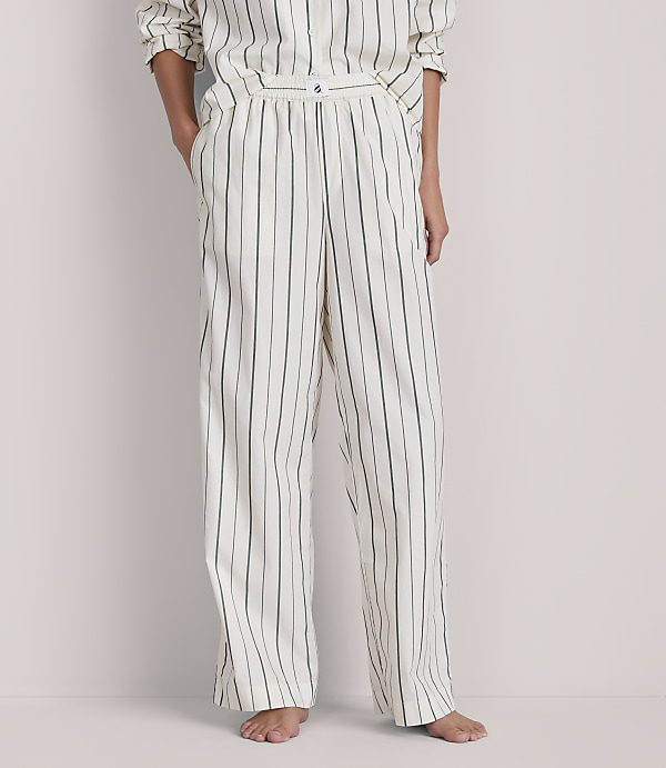 A person stands in striped pajamas against a plain background.