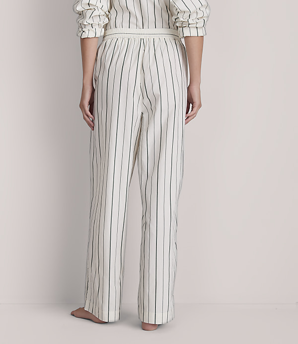 A person stands in striped pajamas against a plain, light-colored background.