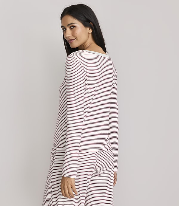 A woman in striped pajamas poses against a plain, light gray background.