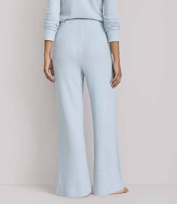 A person stands in light blue waffle-knit pajamas against a plain, light gray background.