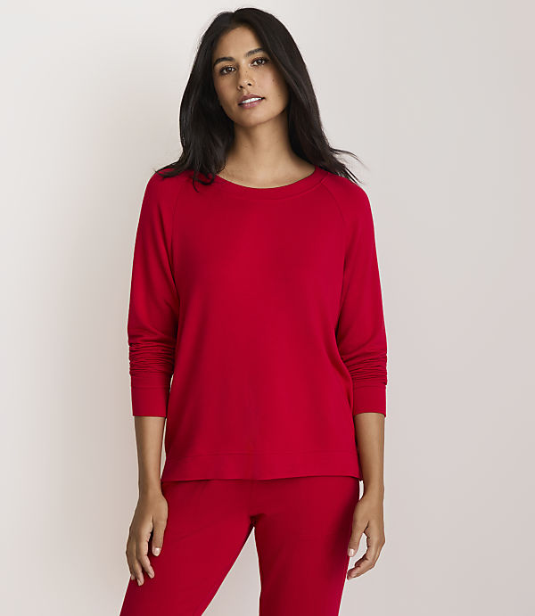 A woman in a red top and pants stands against a plain white background.