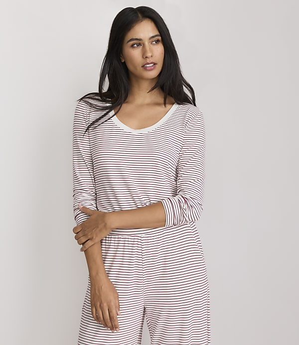 A woman in a striped pajama set stands against a plain white background.