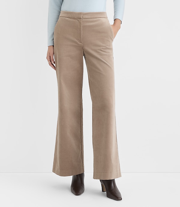 A person stands in front of a plain white background, wearing light blue long sleeves and tan corduroy pants with brown boots.