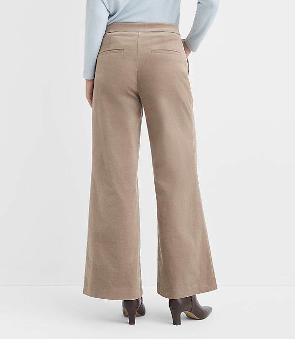 A person wearing wide-leg corduroy pants and brown heeled boots stands against a plain white background.