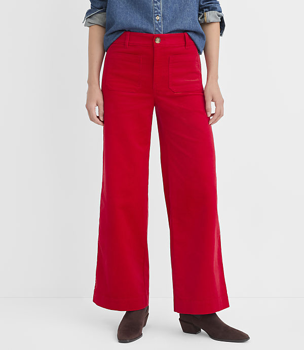 A person stands in bright red wide-leg pants and brown boots against a plain white background.