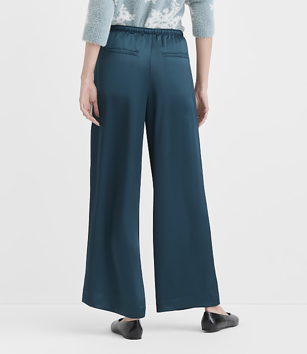 A person stands in teal wide-leg pants and black flats against a plain white background.