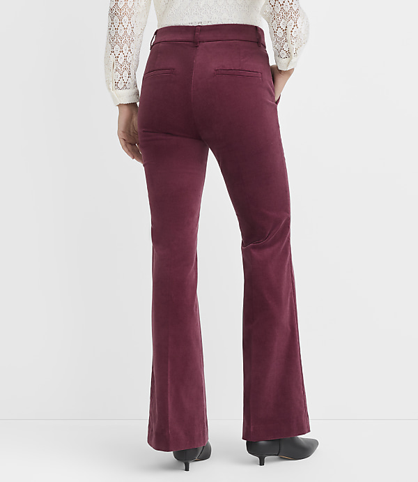 A person wearing burgundy corduroy flare pants and a white lace-trimmed top stands against a plain white background.