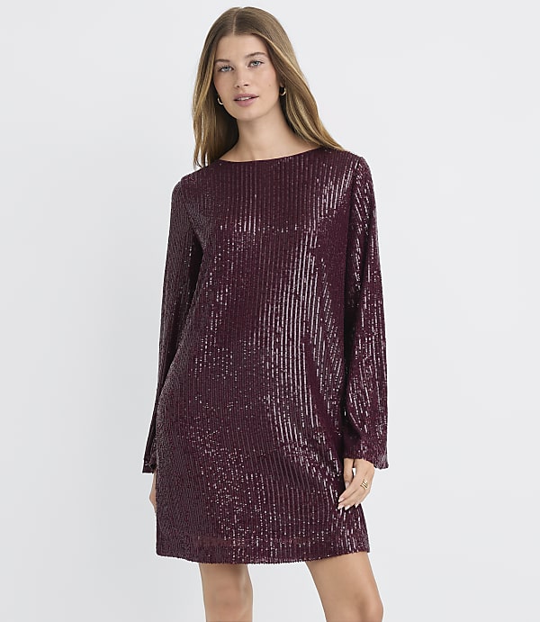 A woman in a burgundy sequined dress stands against a plain white background.