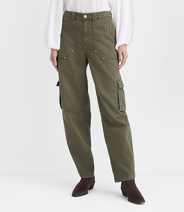 A person wearing a white blouse, olive green cargo pants, and dark brown ankle boots stands against a plain white background.