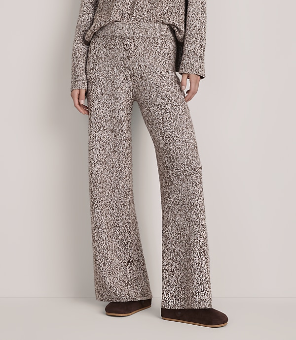 A person wears a matching brown and white textured knit set with brown loafers against a plain white background.
