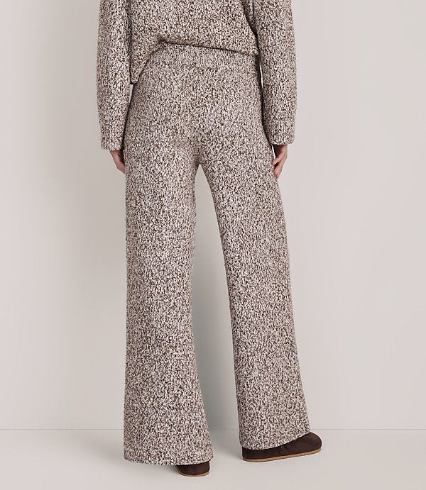 A person wears a matching brown and white textured knit sweater and wide-leg pants against a plain white background.