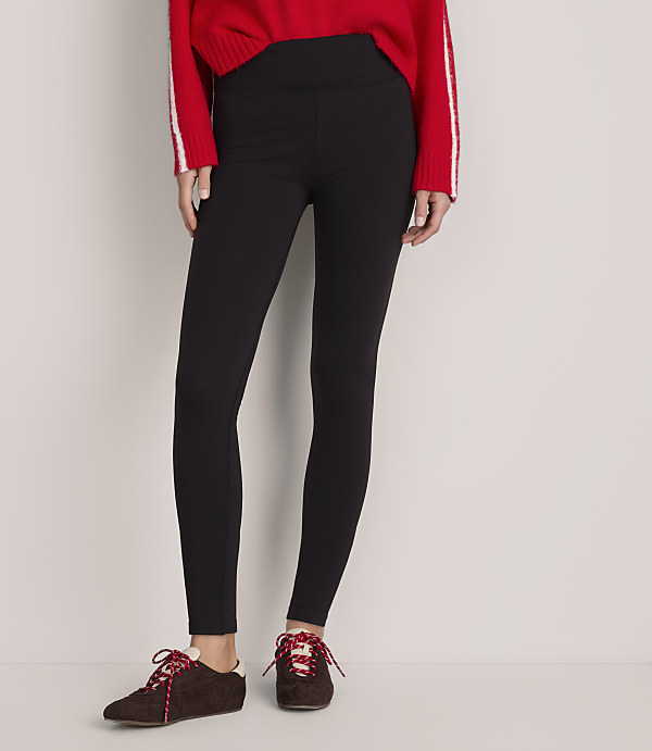A person wearing a red sweater, black leggings, and brown sneakers stands against a plain light gray background.