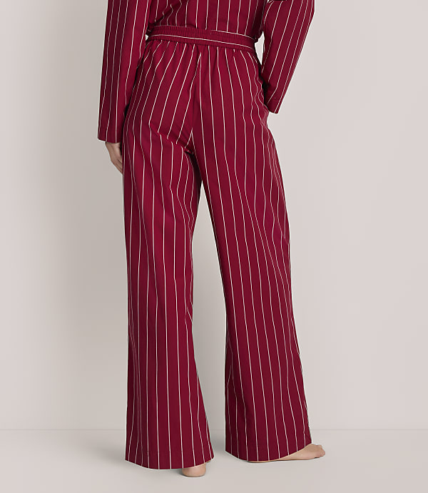 A person wears red and white striped wide-leg pajamas against a plain white background.