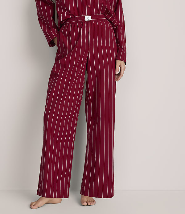 A person wears red and white striped pajamas against a plain, light-colored background.