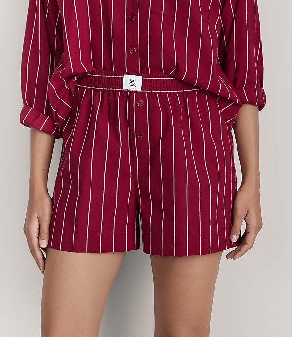 A person wears a red and white striped pajama set against a plain light gray background.