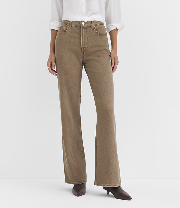 A person in a white shirt and brown flared jeans stands against a plain white background.