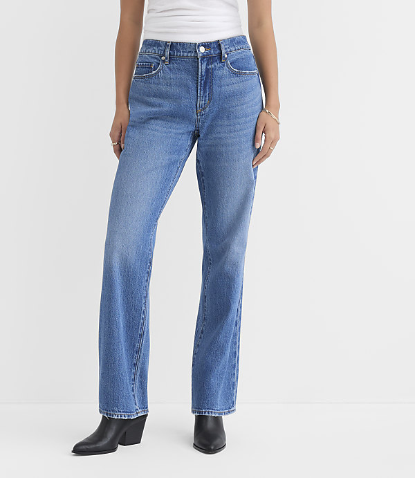 A person wearing blue jeans and black boots stands against a plain white background.