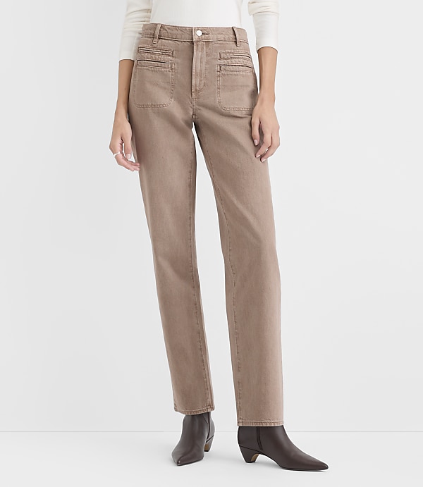 A person wearing a white top, tan trousers, and brown boots stands against a plain white background.