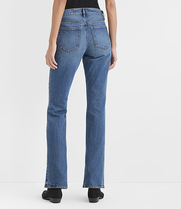 A person wearing blue jeans and black boots stands against a plain white background.