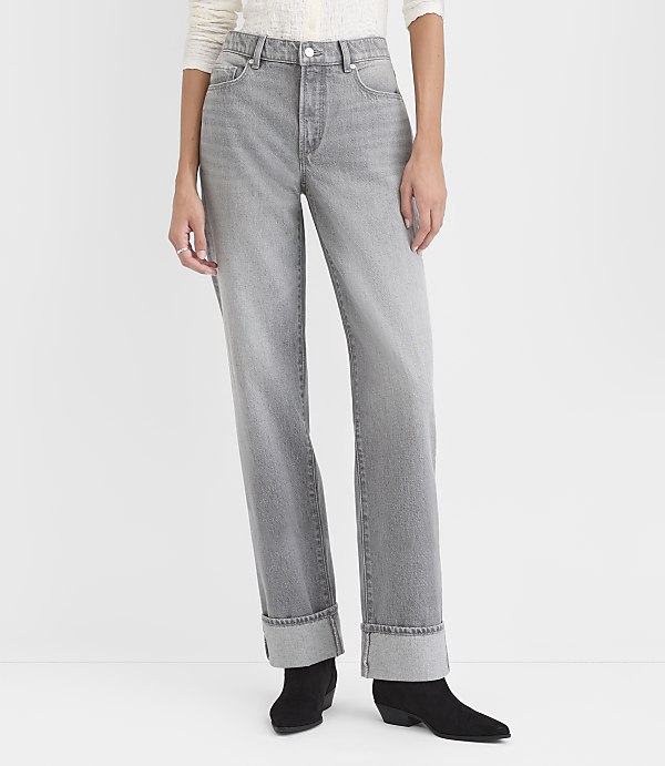 A person wears grey cuffed jeans and black ankle boots against a plain white background.