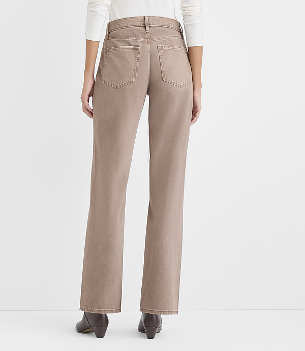 A person wearing a white top, tan wide-leg pants, and brown boots stands against a plain white background.