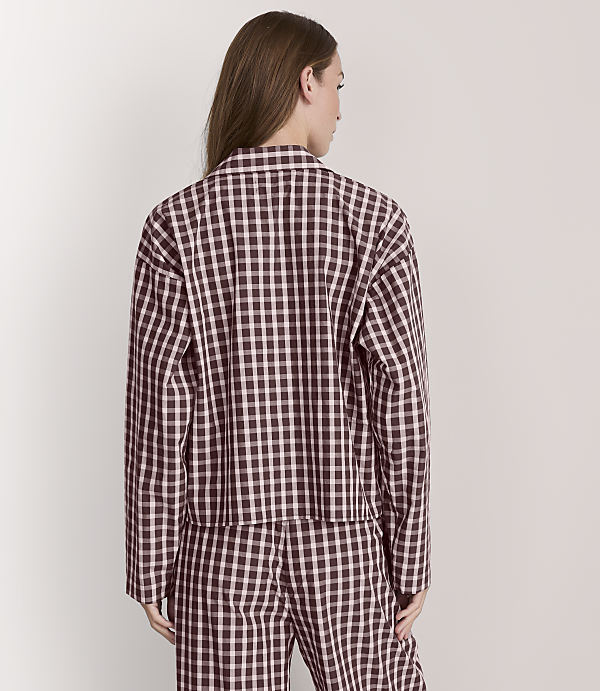 A woman in a black and white checkered jacket and pants stands against a plain white background.