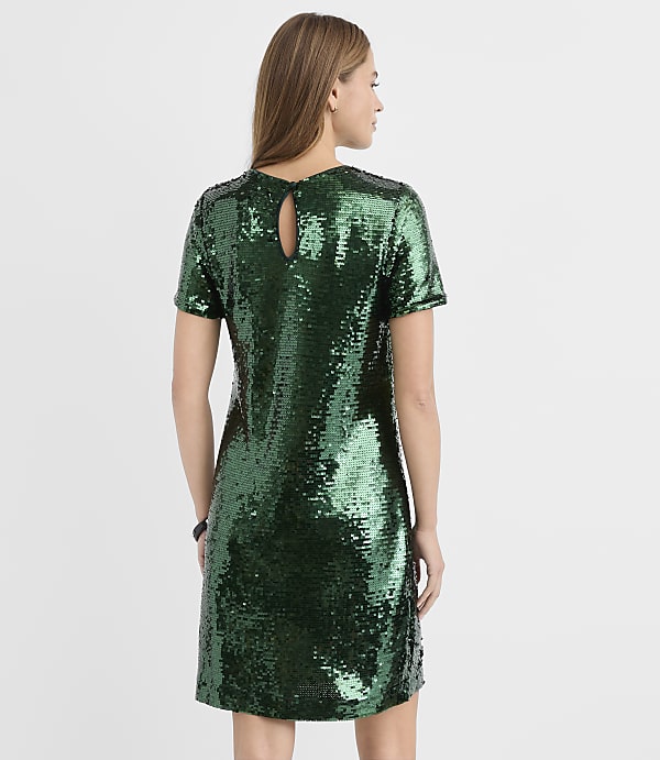 A woman stands with her back to the camera wearing a short-sleeved green sequin dress against a plain white background.