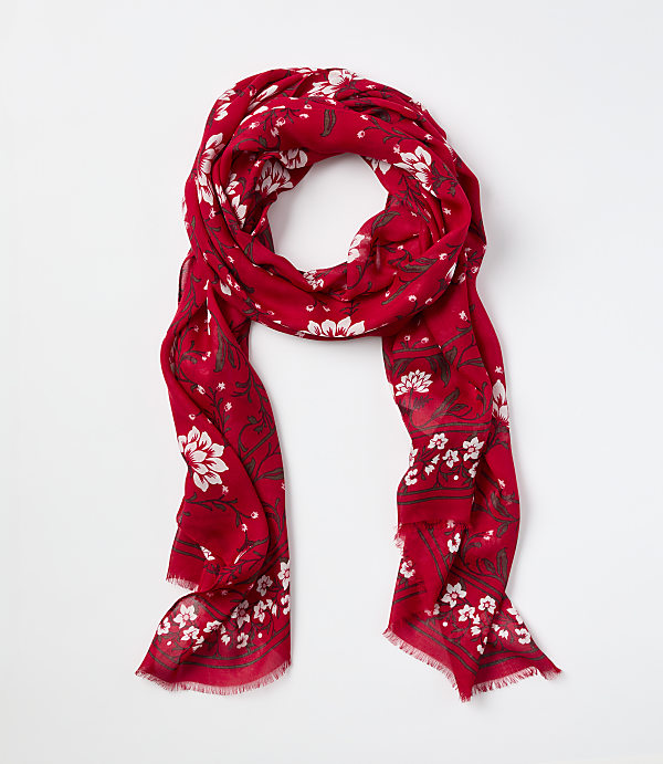 A red scarf with white floral patterns is laid out on a plain white background.