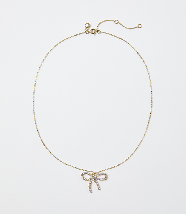 A gold chain necklace with a diamond-encrusted bow pendant rests against a plain white background.