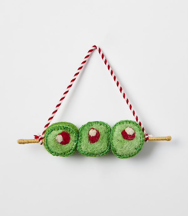 Three green felt sushi rolls on a wooden skewer with a red and white string hanger against a plain white background.