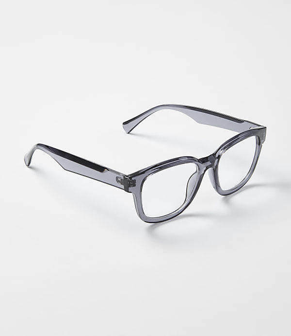 A pair of translucent grey glasses rests on a plain, light-colored surface.