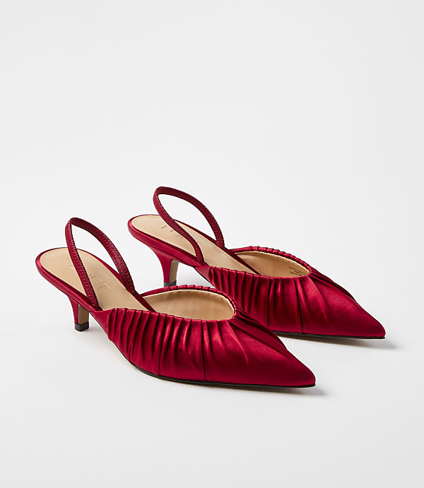 A pair of red satin slingback heels with pleated toes sits against a plain white background.