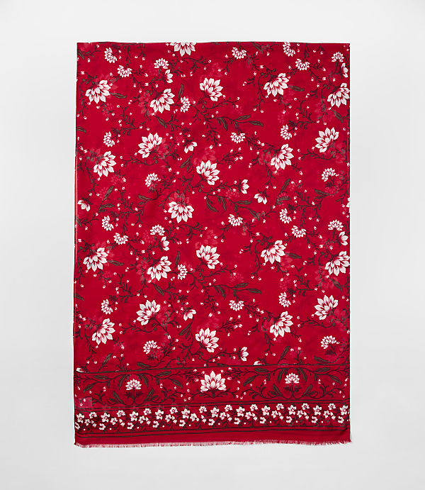A red scarf with white floral patterns is centered against a plain light gray background.