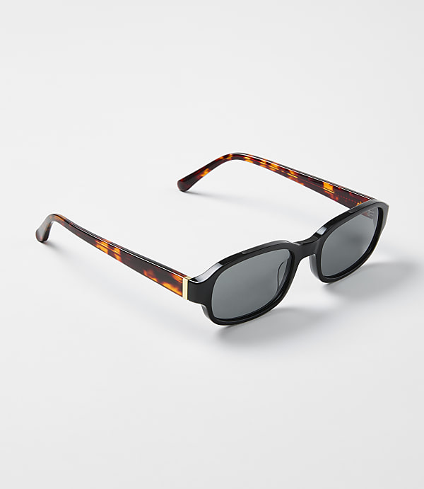 Tortoiseshell sunglasses with black frames rest on a plain white surface.