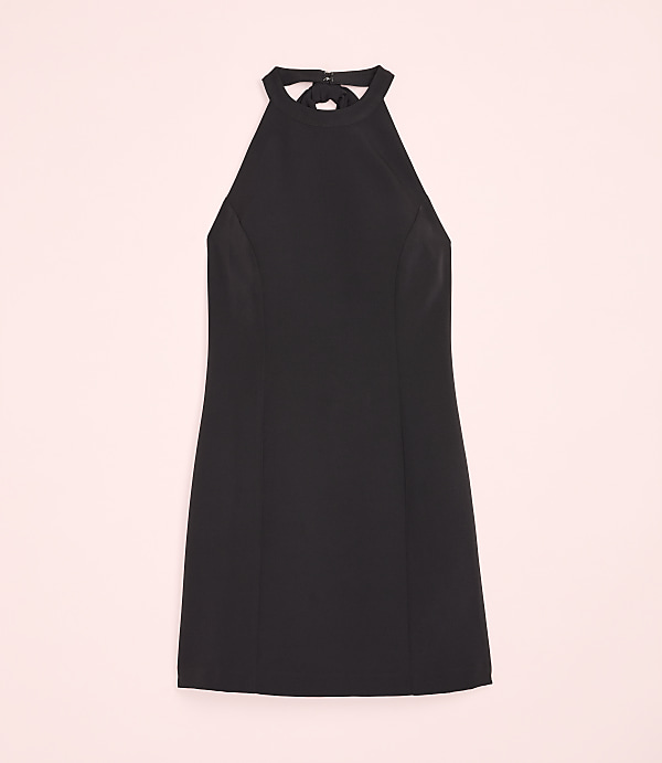 A black halter-neck dress is centered against a solid light pink background.