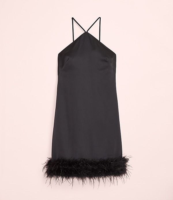 A short black satin dress with feather trim at the hem is centered against a pale pink background.
