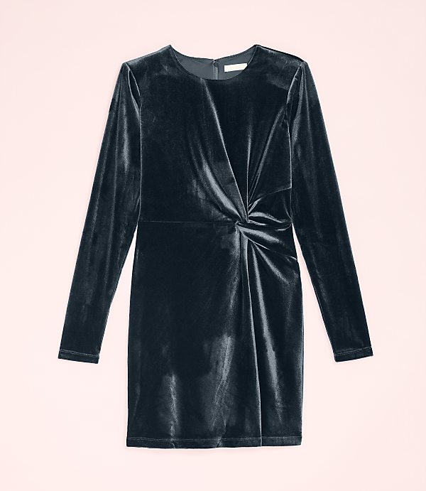 A dark navy velvet long-sleeved dress with a twisted waist detail is centered against a pale pink background.