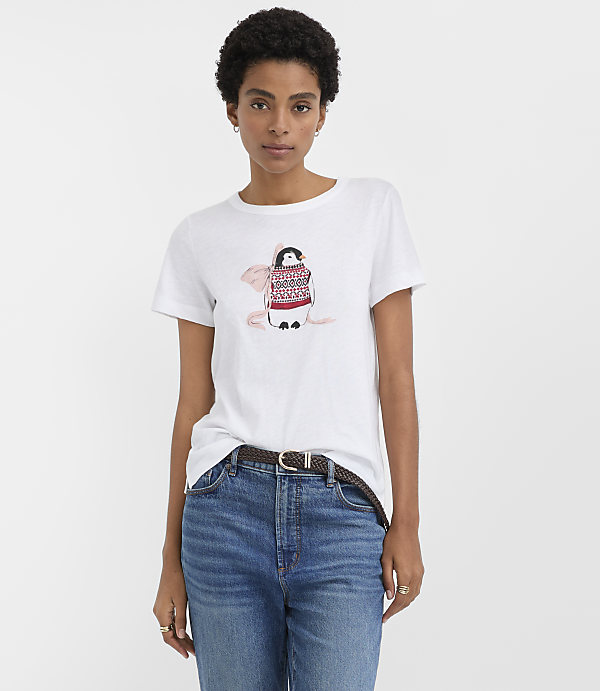 A woman wearing a white t-shirt with a penguin graphic and blue jeans stands against a plain white background.